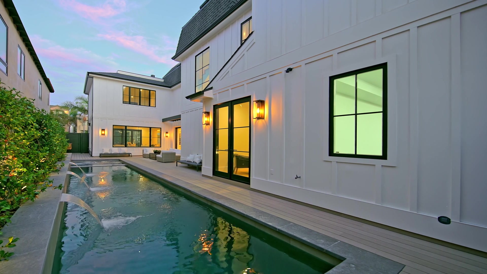 Poolside terrace at dusk, with warm lights along the home