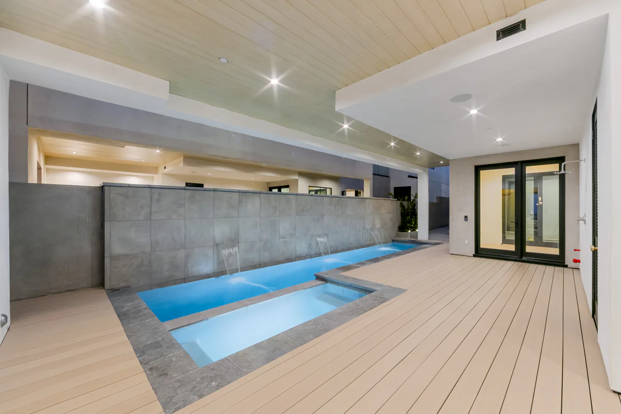 Covered pool and spa beside a wood-paneled terrace