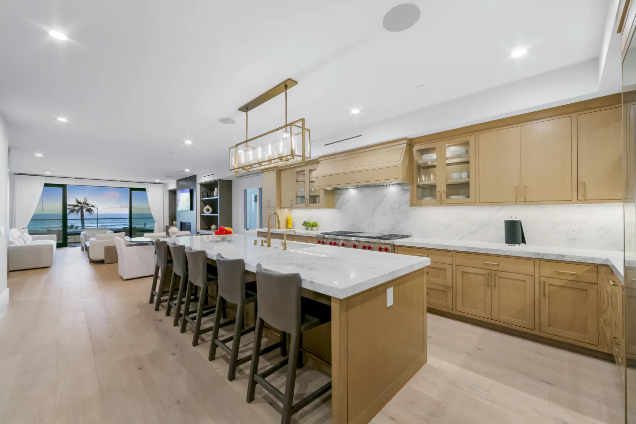 Kitchen with a long stone island, wood cabinetry and ocean beyond
