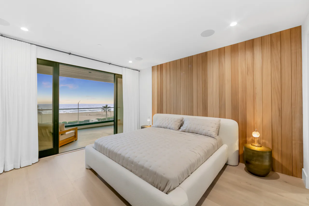 Bedroom with wood feature wall and ocean-facing windows